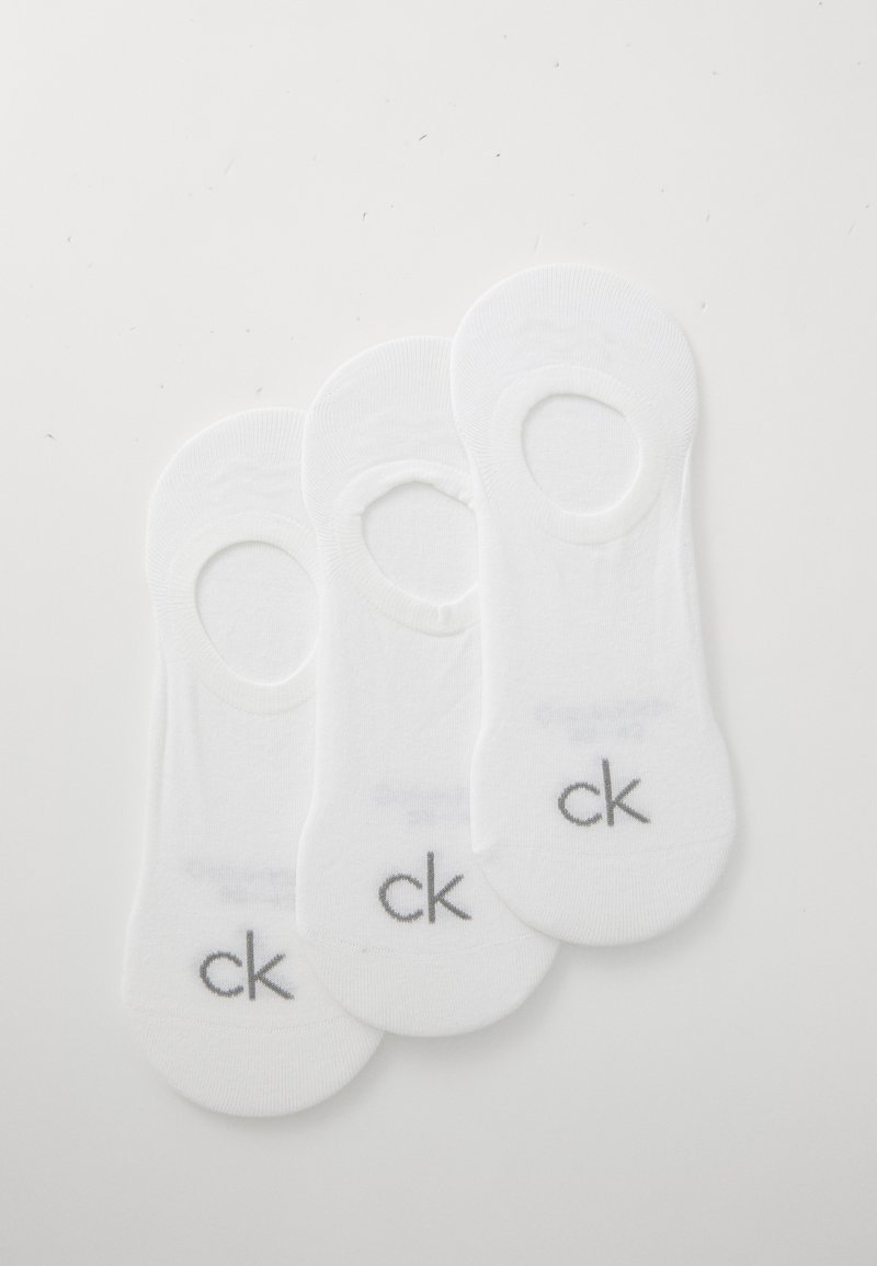 Tres pares de calcetines no-show de algodón blanco con una textura suave y un pequeño logo "ck" gris en el talón.