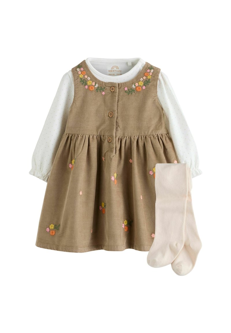 Beige corduroy babyjurk met bloemenbroderie over een witte top met lange mouwen en kleine stippen, gecombineerd met lichtbeige maillots.