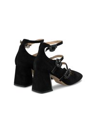 Zapatos de tacón de ante negro con punta afilada, tacón ancho y bloque, y múltiples correas con acentos de joyas a cada lado.