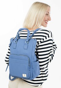 Blue nylon backpack with dual top handles, adjustable straps, zippered main compartment, front pocket, and side drink holder.