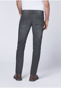 Gray denim jeans with a slim fit, featuring back pockets and a leather patch on the waistband. Worn with brown shoes.