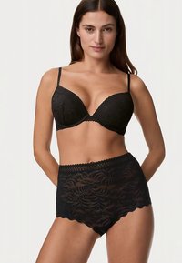 Černá krajková podprsenka a vysoké kalhotky, zdobené květinovými vzory, vroubkovanými okraji a nastavitelnými ramínky. Jemná, texturovaná látka.