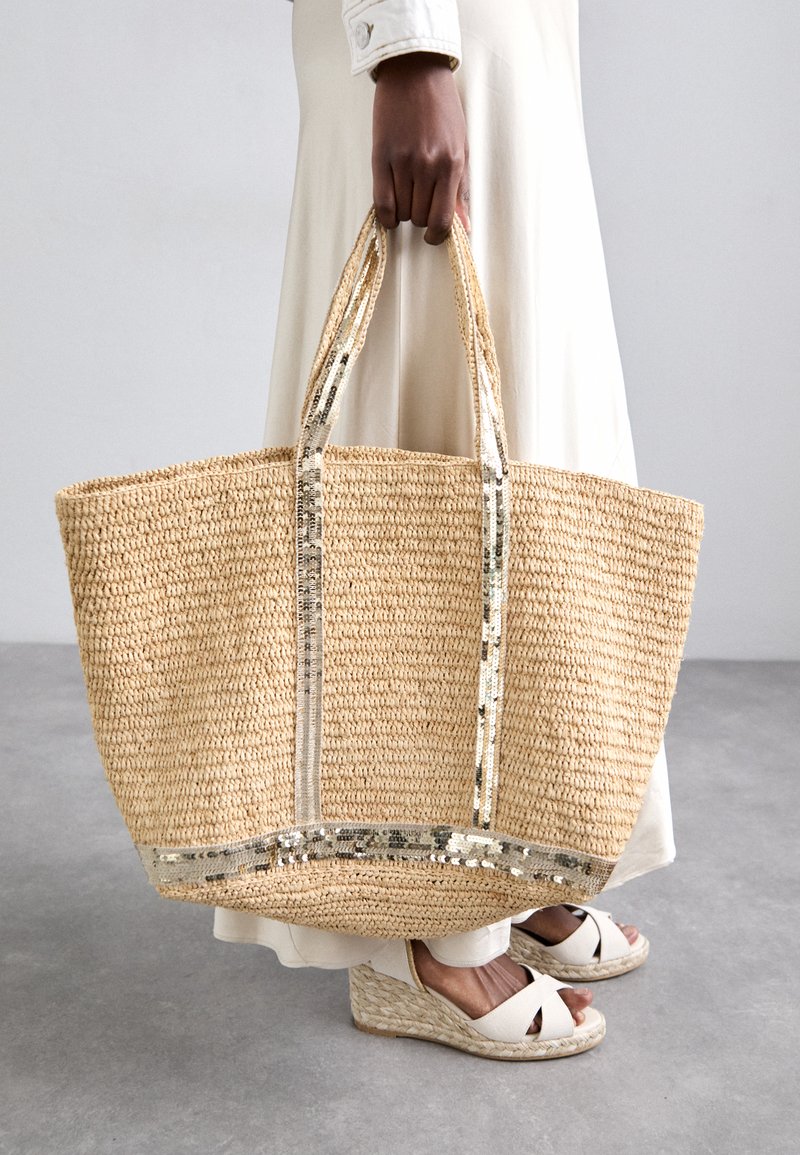 Bolso de paja tejido con acentos de lentejuelas metálicas y asas dobles, que presenta una forma rectangular espaciosa en tonos beige naturales.