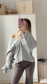 Sweatshirt oversized gris clair avec des épaules tombantes et un col large. Associé à un pantalon marron ajusté à la coupe côtelée. Tissu texturé, coupe décontractée.