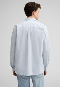 Hellblau gestreiftes Hemd aus Baumwolle mit einem Button-Down-Kragen, langen Ärmeln und einer lockeren Passform. Die Rückseite ist schlicht mit einer Yoke-Näht.