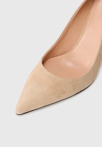 Beidz ir suede augstpapēžu kurpes ar smailu purngalu un gludu iekšējo oderi. Tām ir eleganta silueta un smalka melna zole.