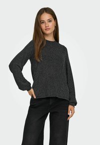 Maglione a righe nere a maniche lunghe con scollo rotondo, trama a coste e vestibilità rilassata, abbinato a jeans neri a vita alta.