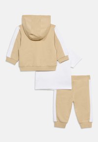 Μπεζ και λευκό σετ ρούχων τριών τεμαχίων για νήπια με ζακέτα με κουκούλα, κοντομάνικο πουκάμισο και παντελόνι, το καθένα με λευκές ρίγες στο πλάι.