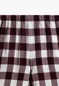 Spodnie w burgundowym i białym kratkę z elastycznym pasem, wykonane z miękkiej, teksturowanej tkaniny, z wyraźnym wzorem kraty na powierzchni.
