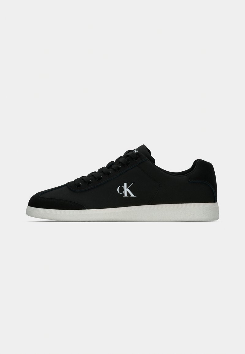 Black sneaker with smooth leather and suede accents, featuring a white sole and a small white logo on the side. Classic lace-up design.