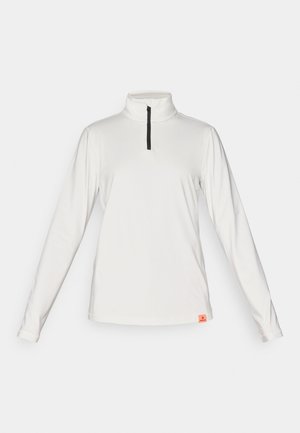 Haut de performance à manches longues, blanc, avec un col haut et une fermeture éclair quart de manière. Présente une fermeture éclair noire et une petite étiquette de marque orange au bas.