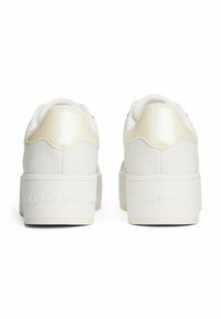 Baskets plateformes blanches avec un panneau arrière texturé, un design minimaliste et un logo "TOMMY JEANS" en relief sur le talon.