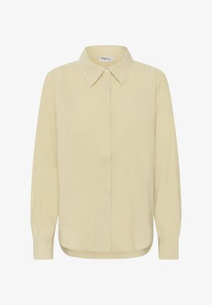 Kreemjas pikkade varrukatega nööpidega särk terava kraega, esikülje peidetud nööpide ja kergelt ümarate servadega.