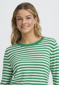 Pull rayé vert et blanc avec un col rond et des manches longues, confectionné dans un tissu doux à la finition lisse.