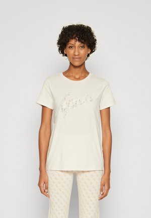 Camiseta de color beige claro hecha de una tela suave, con un diseño del logo "Guess" brillante. Manga corta y escote redondo.