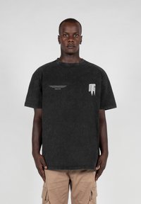 Black oversized cotton t-shirt with a crew neckline, featuring white graphic details on the front. Smooth texture and relaxed fit.