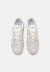 Adidași gri deschis din materiale din suede și plasă. Caracteristici includ vârf perforat, accente crem și un toc cu nuanță albastră. Șireturi texturate.