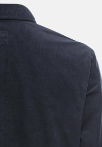 Ciemnoniebieski sztruks o pionowych prążkach, z klasycznym kołnierzem i gładką teksturą, z naciskiem na okolicę dekoltu i ramion.