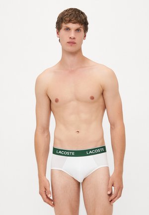 Vita korta underkläder med en grön Lacoste-märkt midjeband, med en figurnära design och slät textur.