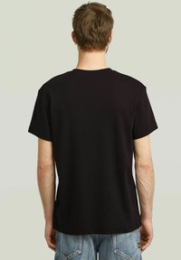 Camiseta negra de manga corta con cuello redondo, hecha de una tela suave, que presenta un corte relajado y sin marcas ni patrones visibles.