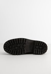 Zwarte rubberen zool met een diepe, gestructureerde loopvlakpatroon en het "Bianco" logo. Kenmerkt zich door versterkte randen en grip elementen voor grip.