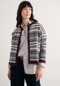 Knit cardigan in multicolored geometric patterns, featuring a maroon ribbed collar and cuffs, with buttons down the front.