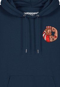 Sweat à capuche bleu marine en tissu doux, avec un design graphique rond sur la poitrine représentant un personnage musclé et des accents rayés rouges.