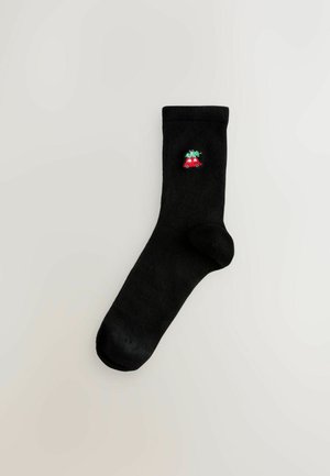 Schwarze Baumwollsocke mit einem gestickten roten Autodesign am Knöchel. Glatte Textur mit passgenauer Form und geripptem Bündchen.