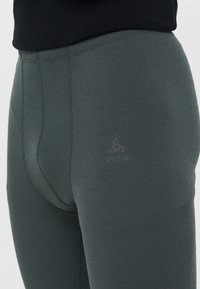 Tummanvihreät, istuvat leggingsit, jotka on valmistettu sileästä, joustavasta materiaalista. Niissä on huomaamaton logo vyötärön lähellä ja saumaton muotoilu.