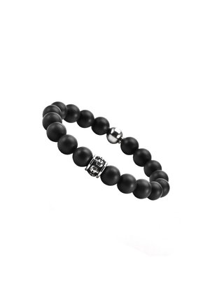 Bracelet en perles noires fabriqué avec des perles d'onyx mat, avec un accent en métal gravé d'une tête de mort et un fermoir en métal lisse. Forme ronde, design extensible.