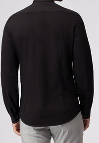 Camisa negra de manga larga con dobladillo curvado, sutil brillo y puños abotonados, que presenta un cuello clásico y una textura suave.