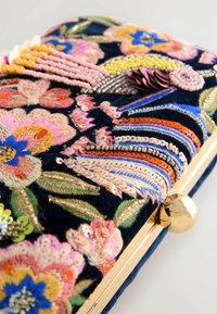 Embroidered clutch with colorful floral patterns in pink, blue, and gold on dark fabric. Features gold hardware and sequined accents.