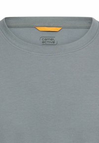 Grå bomulds T-shirt med rund hals og tekstureret finish samt en kontrasterende gul detalje på indersiden af halsudskæringen. Brandlogo trykt indvendigt.