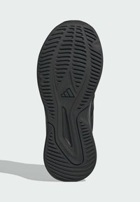 Semelle de chaussure en caoutchouc noir avec des rainures texturées pour l'adhérence, présentant un logo distinctif et un design incurvé pour la stabilité. Attribution non marquante mentionnée.