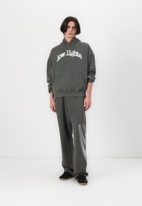 Sweatshirt cinza oversized com o texto "low lights" em branco, acompanhado de calças de moletom cinza combinando com um design gráfico em branco. Ténis pretos.