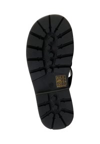 Semelle noire en caoutchouc d'une chaussure avec des crampons profonds, des motifs hexagonaux et linéaires, et une petite étiquette marquée affichant des icônes d'entretien de chaussure et le texte "Fabriqué en P.R.C.".