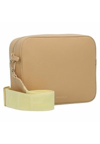 Sac bandoulière en cuir beige avec une texture lisse, de forme rectangulaire, fermeture éclair dorée et une bandoulière jaune réglable arborant un motif de logo.