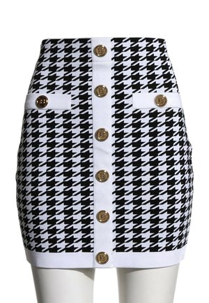 Mini-jupe pied-de-poule noir et blanc avec bordure blanche, boutons dorés au centre et deux pattes décoratives boutonnées aux hanches.