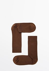 Brune ribbede sokker med en struktureret overflade, der har en glat manchet og rund tå, arrangeret i et par.