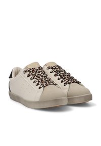 Zapatillas con parte superior de cuero crema, cordones con estampado de leopardo y un panel texturizado negro en el talón. Suela de goma con puntera redondeada.