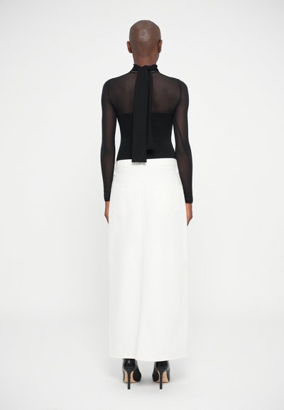 Sort langærmet bodysuit med en slips ved halsen, parret med en hvid højtaljet maxi-nederdel og sorte hæle. Minimalistisk design.