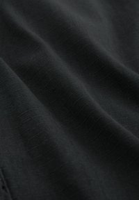 Crni materijal s teksturiranom površinom i suptilnim horizontalnim linijama. Materijal izgleda lagano i glatko s blagim sjajem.