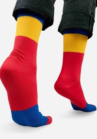 Kolorowe skarpetki załogowe z czerwonymi, żółtymi i niebieskimi sekcjamii o gładkiej teksturze. Design zawiera jednolite bloki kolorowe i wzmocnione mankiety.