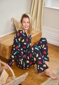 Schwarzes Pyjama-Set mit bunten New-York-Motiven, darunter Taxis, Eiscreme und die Freiheitsstatue, mit kontrastierenden roten Akzenten.