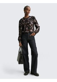 Zwart en paars gemÃkt longsleeve shirt met pofmouwen, gecombineerd met donkerblauwe flared jeans. Gecombineerd met een zwarte handtas.