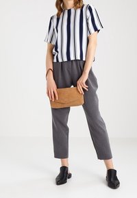 Raidallinen lyhythihainen paita laivastonsinisellä ja valkoisella, harmaat housut, mustat slip-on-kengät ja vaalea laukku. Sileä kangas ja rento istuvuus.