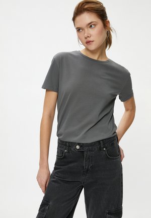 Graues Baumwoll-T-Shirt mit kurzen Ärmeln und rundem Ausschnitt, kombiniert mit hochgeschnittenen schwarzen Denim-Cargo-Hosen mit Seitentaschen.
