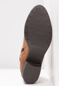Botte en cuir marron avec une semelle en caoutchouc texturée, une fermeture éclair latérale et un design classique. Taille 38 indiquée sur la semelle. Remarquable pour sa durabilité.