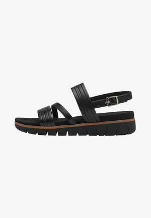 Sandali in pelle nera con più cinghie orizzontali, fibbia regolabile e una suola spessa e texture che presenta un leggero accento marrone.