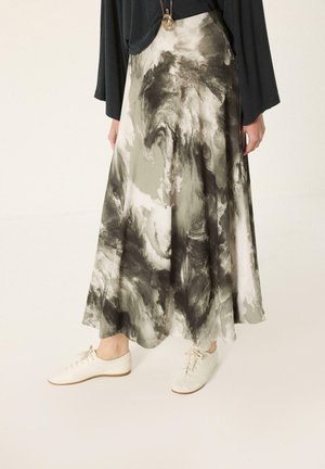 Jupe fluide longue jusqu'à la cheville avec un motif marbré abstrait noir, blanc et gris, associée à des chaussures blanches à lacets et un haut noir à manches longues.